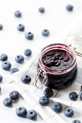 Blueberry jam with fresh berries on white marble table background. Selective focus.