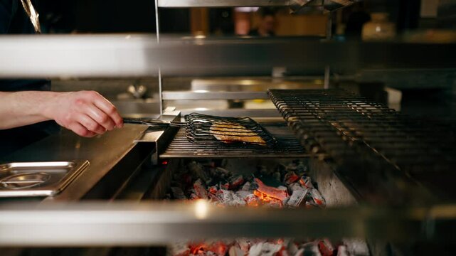 in a Japanese restaurant chef in a blue uniform fries fish on the grill in the kitchen