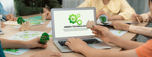 Green technology logo displayed on green business laptop while business team presenting green...