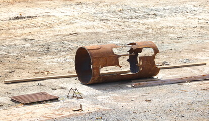 A scarred old rusty piece of metal pipe lies on the sand