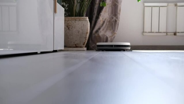Robot vacuum cleaner vacuuming the floor in the bedroom. Smart home with automated devices that simplify life. A smart vacuum cleaner cleans the floor