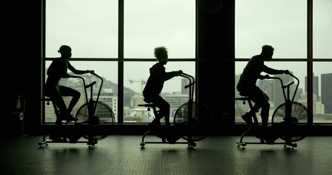People bicycle machine and fitness in gym for exercise commitment and silhouette in sports club. Spin class group and cycling on equipment with motivation cardio and endurance or weight loss