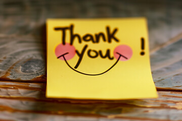 In high definition, the camera captures the essence of gratitude on a yellow sticky note, where the words "Thank you!" stand out in a playful, expressive style, coupled with a char