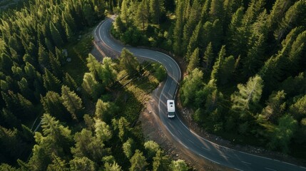Modern mobile home on serpentine mountain road through summer coniferous forest aerial view