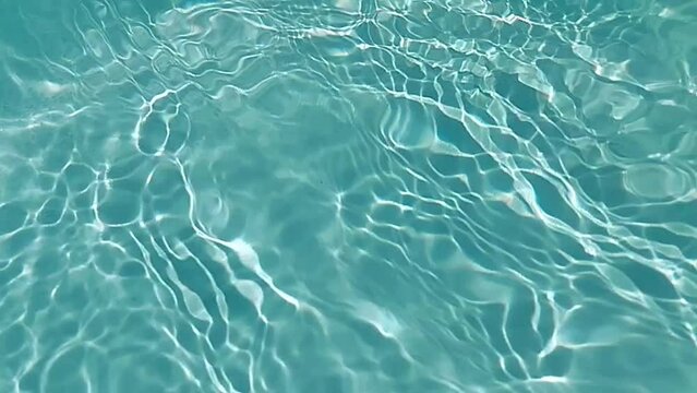 Blue water with ripples on the surface. Defocus blurred transparent blue colored clear calm water surface texture with splashes and bubbles. Water waves with shining pattern texture background.