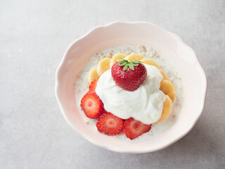 close-up view delicious strawberry on top of creamy yogurt in bowl of porridge with banana slices