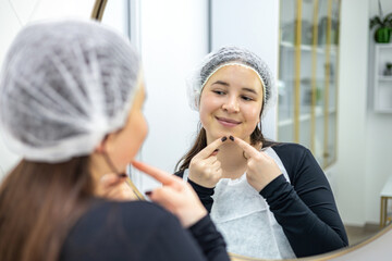 Skincare, mirror and woman popping acne on face with hands, dirt or scar on skin. Dermatology, facial wellness and girl in bathroom to squeeze pimple, checking reflection or morning routine