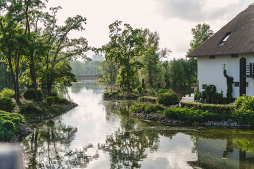 Landscape in a city park, lake, river and cottages against the backdrop of a lawn and beautiful landscaping with stones