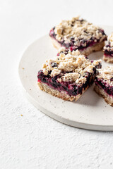 Baked oatmeal bars or crumble squares with fresh blueberry on white background, text space. Menu, recipe