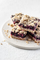 Baked oatmeal bars or crumble squares with fresh blueberry on white background, close up. Menu, recipe