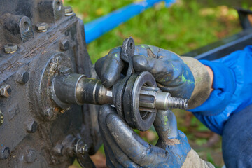 replacement of the release bearing in the walk-behind tractor, a man in gloves repairs the transmission clutch of a walk-behind tractor, repair of a walk-behind tractor