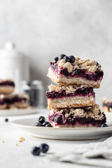 Baked oatmeal bars or crumble squares with fresh blueberry on white kitchen background, text space. Menu, recipe