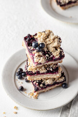 Baked oatmeal bars or crumble squares with fresh blueberry on white background, close up. Menu, recipe