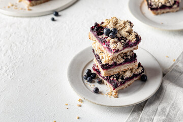 Baked oatmeal bars or crumble squares with fresh blueberry on white background, close up, text space. Menu, recipe