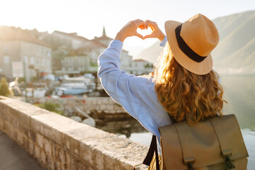 Woman tourist making heart shape with her hands, enjoying panoramic view of city  and famous landmarks.  Lifestyle, travel, tourism, active life.