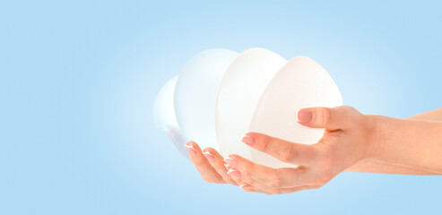 Variety of breast implants in hands on blue background. Copy space