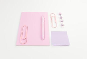 Top view of pink notebook on white background. Sticky note, paperclips, pen and pins. School, office wallpaper. Flat lay, copy space.