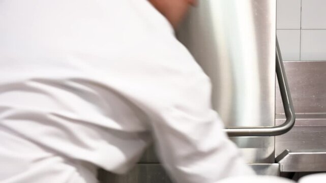 Woman putting dirty dishes in industrial dishwasher at the commercial kitchen. High quality 4k footage