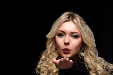 Woman blowing kiss, blonde curls, black turtleneck