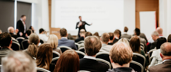 Speaker giving a talk in conference hall at business event. Rear view of unrecognizable people in...