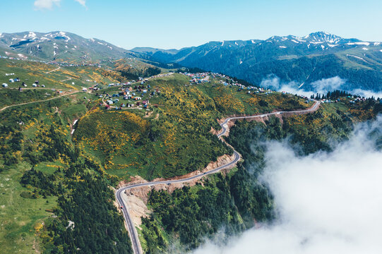 Aerial Drone view of Gomismta village, secluded mountain resort in Georgia, nestled above clouds in Guria region, green landscapes and winding roads leading through serene alpine environment.