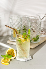A refreshing summer drink or alcoholic cocktail with passion fruit, ice and lemon on a sunny day. A fresh healthy cold lemonade drink. Sparkling water with lemon.