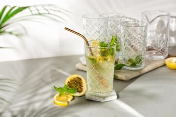 A refreshing summer drink or alcoholic cocktail with passion fruit, ice and lemon on a sunny day. A fresh healthy cold lemonade drink. Sparkling water with lemon.