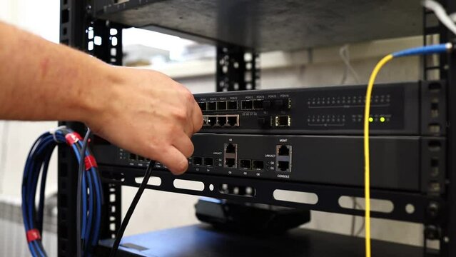 Network technician connects and checks cables on a network switch