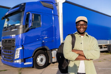 Portrait of cheerful trucker standing by his truck vehicle ready for transport.