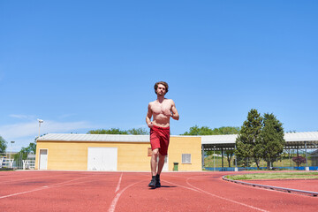 Naklejka premium man training on a running track. general view of a shirtless man running.