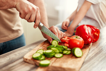 A parent and a child bond and learn by preparing fresh vegetables in the kitchen