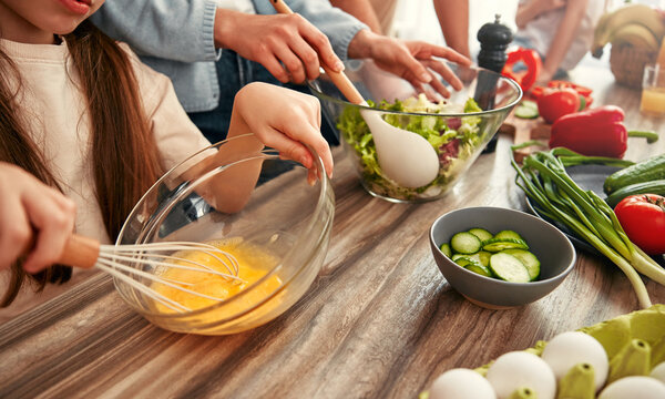 Family spends quality time making a nutritious salad in their contemporary kitchen
