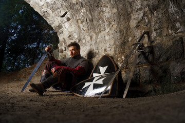 Crusader knight in armor with sword in castle ruins in Europe