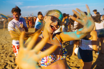 Holi festival. Young people with colorful paint on clothes and bodies have fun together. Beach party. Friendship, rest, holidays.