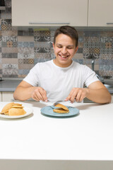 A young man eating in the kitchen.