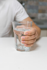.A young man drinking water in the kitchen.