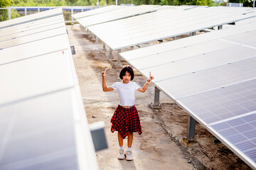 Cute little girl happily walks alone on a solar cell farm, standing in front of solar panels.