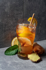 Iced tea with mint, ginger, and lemon on a grey background.