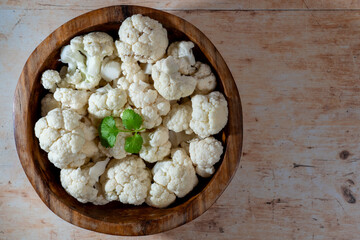 Freshly cut cauliflower florets in wooden bowel on table.  Top view.