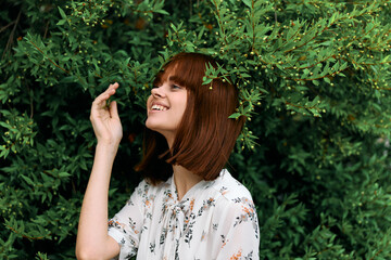 Vibrant redhaired woman standing gracefully in front of lush green foliage