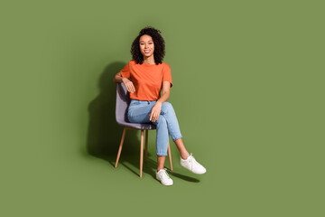 Full size photo of pretty young girl sit chair smile wear trendy orange outfit isolated on khaki...