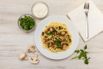 Spaghetti Pasta with mushrooms on light, wooden background, top view, copy space. Homemade italian pasta with champignon mushroom.   