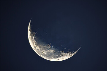 A crescent moon with a white glow against a dark blue night sky