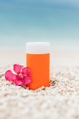 Bright sunscreen bottle on pebble beach with sea as background. Concept of minimalist design of advertisement of sunscreen or cosmetics. Protection against ultraviolet rays or harmful effects of sun