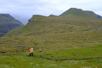 Mountain trip from Saksun village of Saksun to Tjornuvik on island of Streymoy. Silhouettes of hiking people on trail. Faroe Islands, Denmark