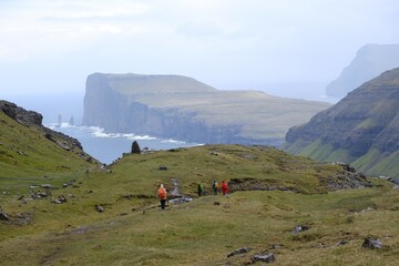 Mountain trip from Saksun village of Saksun to Tjornuvik on island of Streymoy. Silhouettes of hiking people on trail. Faroe Islands, Denmark