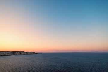 Dawn breaking over the cliffs of Bonifacio and Mediterranean sea on the south coast of Corsica with the coastline of Sardinia in the distance