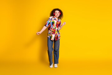 Full body photo of pretty young girl dancing listen music wear trendy colorful print outfit isolated on yellow color background