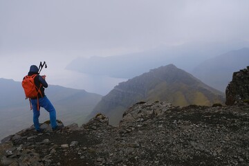 Silhouette of person on peak on foggy day. Eysturoy Island and climbing  highest peak of Faroe Islands - Sl&aelig;ttaratindur, Denmark. 