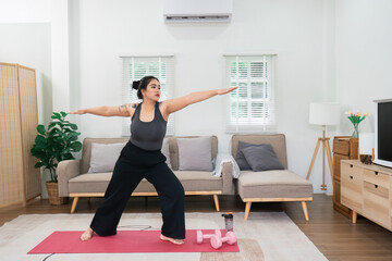 Obraz premium Overweight Woman Practicing Yoga at Home for Wellness and Fitness in a Modern Living Room